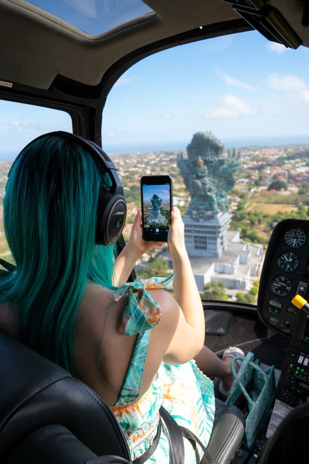 Passenger photographing the coastline through an open helicopter window