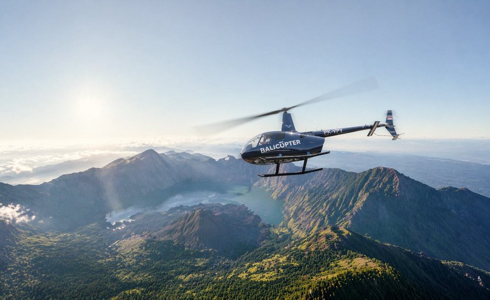 Four-seat turbine helicopter in cruise above a volcanic ridge