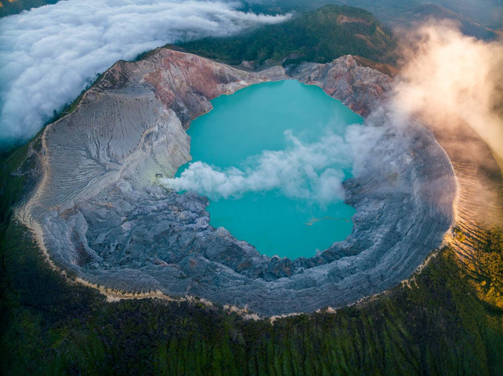 Turquoise crater lake ringed by steaming rock